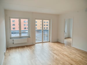 Inflyttningsklar lägenhet med ljus tom yta, trägolv, stora fönster och balkongdörr