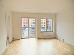 Inflyttningsklar lägenhet med ljusa väggar, trägolv, balkongdörr och fönster