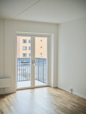 Inflyttningsklar lägenhet med ljus ekparkett och balkongdörr mot innergård