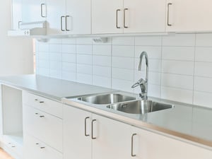 Inflyttningsklart kök med vita skåpluckor, dubbel diskho och kaklad vägg