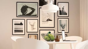 Vitt matbord med laptop, skål med grönsaker och vägg med inramad konst i ljus interiör