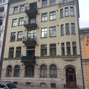 Flerfamiljshus med fasad i beige puts, balkonger och välvda fönster