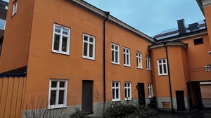 Orange flerbostadshus med vita fönster och innergård