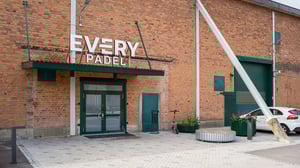 Fasad med entré till Every Padel, tegelvägg, grön dörr och parkerad bil