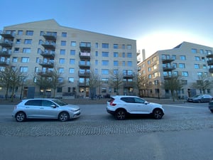 Flerbostadshus med parkerade bilar på gatan