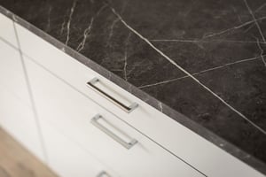 Köksskåp med vita luckor och mörk marmorbänkskiva