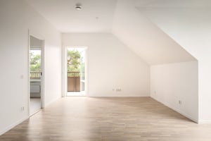 Inflyttningsklart rum med ljusa väggar, trägolv och utgång till balkong