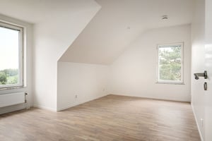 Inflyttningsklar lägenhet med tomt rum, ljusa väggar och fönster mot grönska