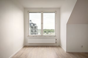 Inflyttningsklar lägenhet med stort fönster och ljusa väggar