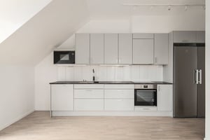 Inflyttningsklar lägenhet med modernt kök, vita skåp och rostfri kyl