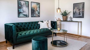 Vardagsrum med mörkgrön soffa, soffbord och konst på väggen