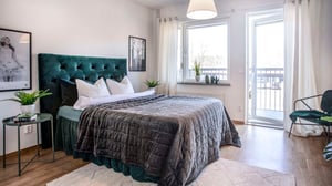 Inflyttningsklart sovrum med dubbelsäng, mörkgrönt sänggavel och ljusa väggar