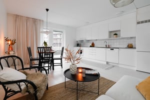 Ljust och stilrent kök med matplats och vardagsrum i öppen planlösning
