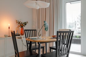 Inflyttningsklart matrum med rund bord, svarta stolar och stora fönster