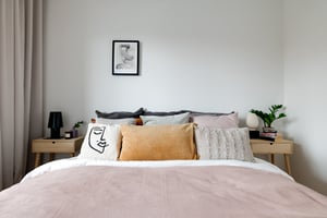 Sovrum med bäddad dubbelsäng, sängbord och väggdekor i ljusa färger