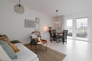 Inflyttningsklart vardagsrum med matplats, ljusa väggar, soffhörna och stora fönster