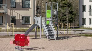 Lekplats med rutschkana, klätterställning och gungdjur i ett bostadsområde