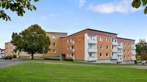 Flerbostadshus i tegel med balkonger och grön gård framför