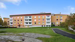 Flerbostadshus i tegel med grön innergård och gångväg