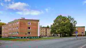 Flerfamiljshus i rött tegel med grönyta och träd utanför