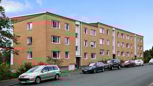 Flerfamiljshus med parkerade bilar utanför