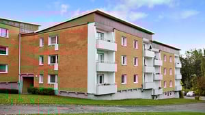 Flerbostadshus i tegel med vita balkonger och grön gård