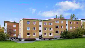 Flerbostadshus i tegel med grön gräsmatta och blå himmel