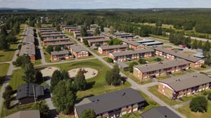 Flygvy över ett bostadsområde med flerbostadshus, grönområden och lekplats