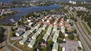 Flygvy över bostadsområde med radhus, flerbostadshus, vägar och vatten