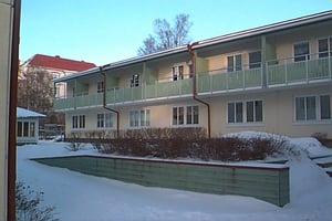 Flerbostadshus med balkonger i vintermiljö, omgivet av snö