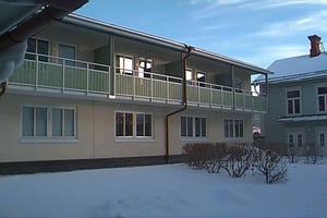 Snötäckt flerbostadshus med balkonger och flera fönster