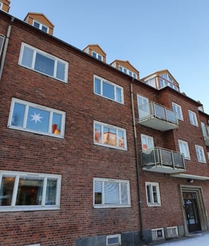 Flerbostadshus i rött tegel med balkonger och många fönster under klar himmel