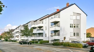 Flerbostadshus med balkonger och parkerade bilar