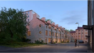 Exteriör bild av bostadshus i kvällsljus med upplysta fönster och en cyklist på gatan