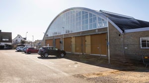 Exteriör av en byggnad med välvd takform och parkerade bilar på gårdsplanen i Helsingborg