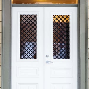 Vita dubbeldörrar med glasinsatser och svart galler