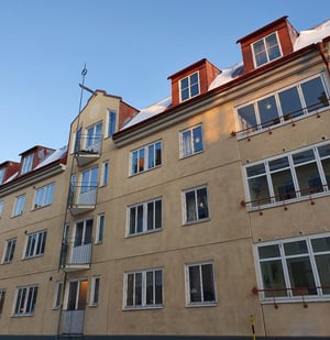 Flerfamiljshus med beige fasad och röda takkupor