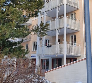 Flerfamiljshus med balkonger och omgivande träd i vintermiljö