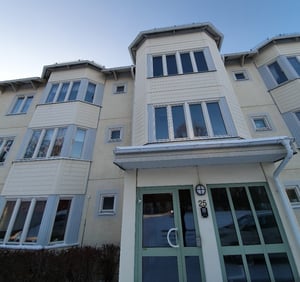 Flerfamiljshus med ljus fasad och gröna entrédörrar