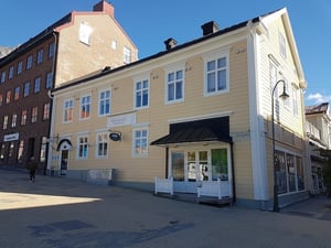 Gul träbyggnad med vita fönster och svart tak i stadsmiljö