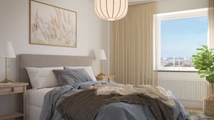 Sovrum med dubbelsäng, sängbord, fönster och ljusa gardiner