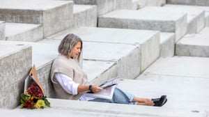 Kvinna sitter och läser på en stentrappa