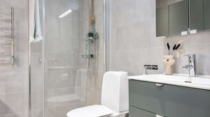 Inflyttningsklart badrum med dusch, handfat och grön badrumskommod