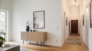 Lägenhet med ljus hall, trägolv och dekorativ skänk