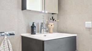 Modernt badrum med handfat, spegelskåp och beige kakel