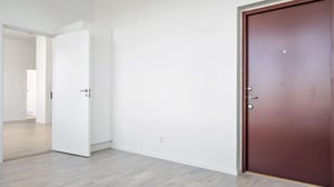 Inflyttningsklar lägenhet med ljusa väggar, grått golv och brun ytterdörr