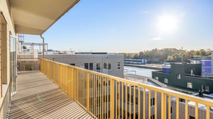 Balkong med gul räcke och utsikt över moderna bostadshus och vatten i solljus