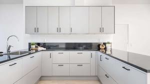 Inflyttningsklart kök med ljusa skåpluckor, svart bänkskiva och diskho