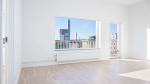 Inflyttningsklar lägenhet med ljusa väggar, stort fönster och utgång till balkong