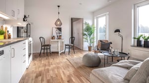 Inflyttningsklar lägenhet med öppen planlösning, ljusa ytskikt, vitt kök och vardagsrum med stora fönster